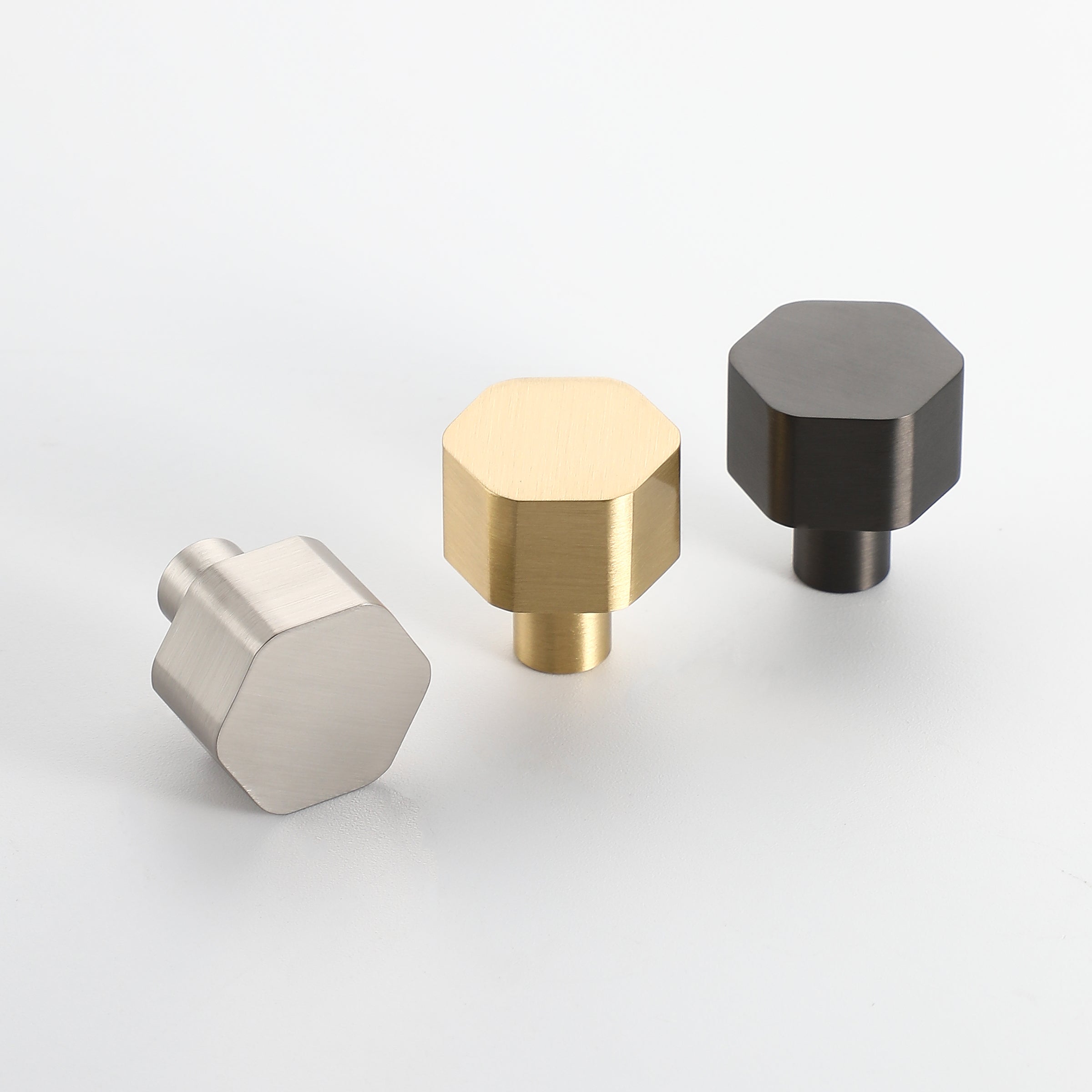 Hexon brass cabinet knobs in brushed nickel, brushed brass, and gunmetal finishes, shown side by side.