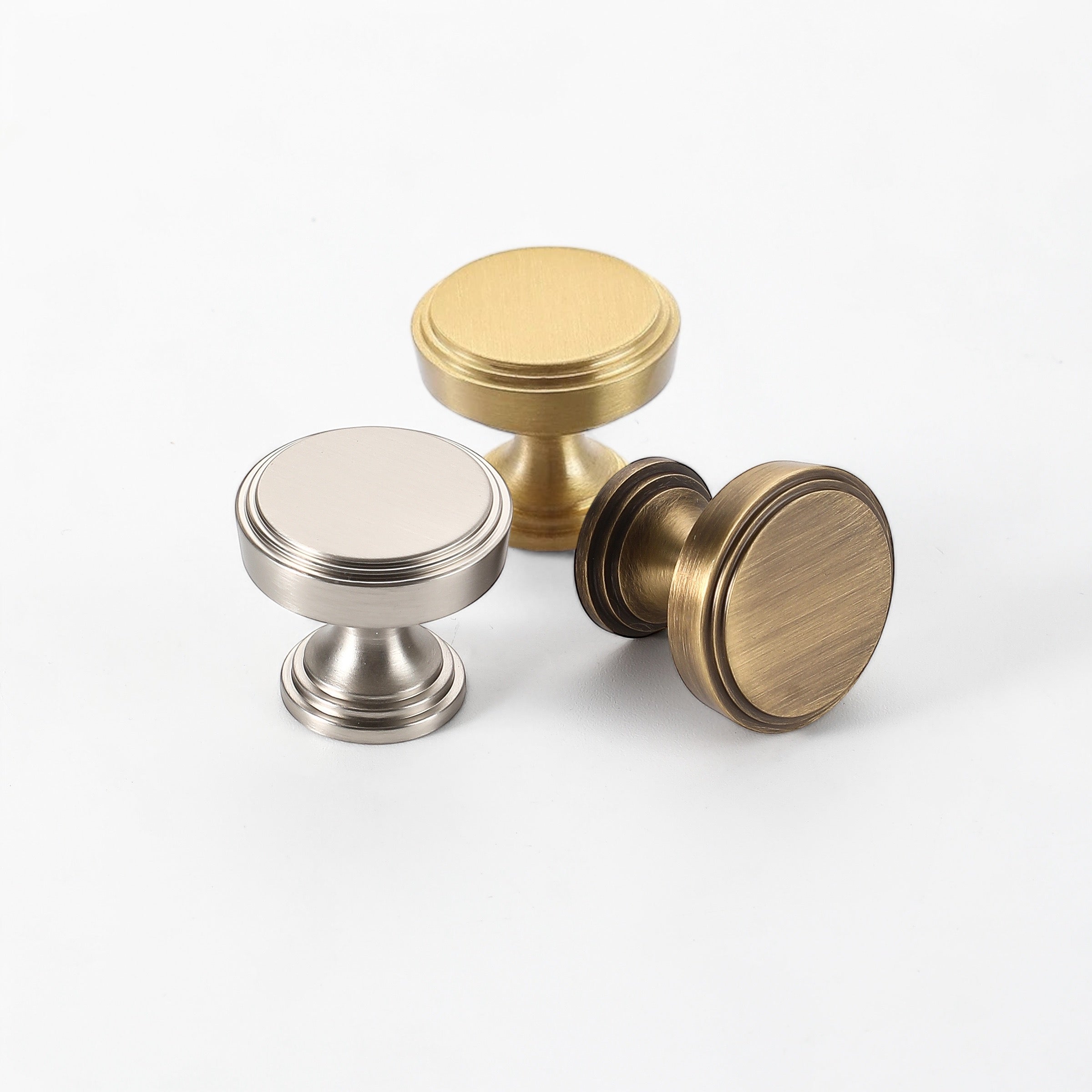 Set of three drawer knobs in brass, antique bronze, and brushed nickel finishes, suitable for cabinets and furniture.