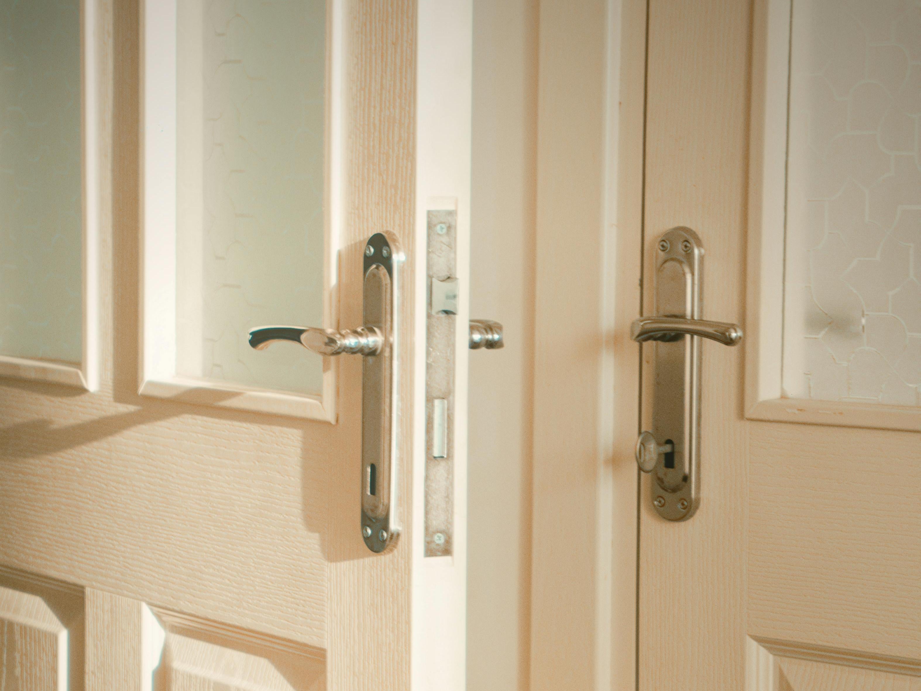 two metallic door handles on cream-colored doors