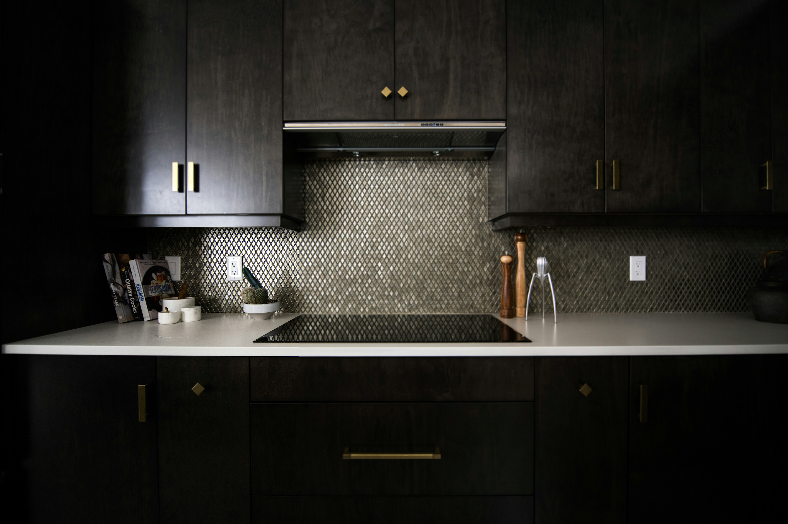 A modern kitchen with dark cabinets featuring brass door handles